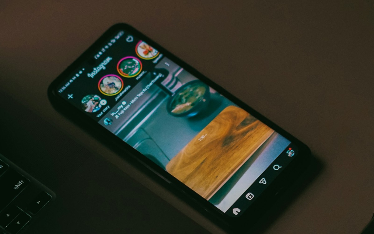 Smartphone con feed Instagram sul tavolo di lavoro, accanto alla tastiera